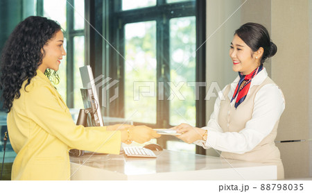 At the airport check-in counter, a passenger hands over his documents to the manager via a counter ticket. 88798035