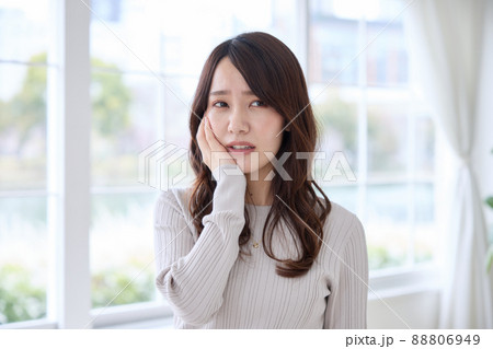 歯が痛くて頬を押さえる女性 歯が痛くて頬を押さえる女性 88806949