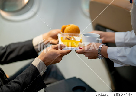 Close-up hands of passenger receive dessert and cake from air hostess or cabin crew during fly 88807447