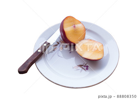 Nectarine and a knife on a porcelain plate. 88808350