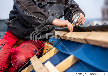 Craftsman or construction worker install a new roof, roofing tools, new metallic roof or metal sheet, building concept 88808984