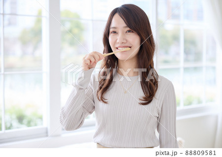 スマホを見ながら歯磨きをする女性 88809581