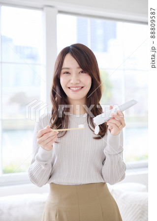 スマホを見ながら歯磨きをする女性 88809587