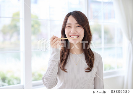 スマホを見ながら歯磨きをする女性 88809589