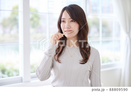 スマホを見ながら歯磨きをする女性 88809590