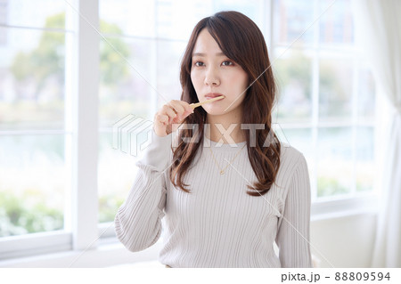 スマホを見ながら歯磨きをする女性 88809594