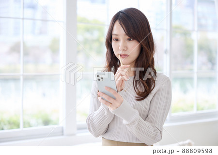スマホを見ながら歯磨きをする女性 88809598