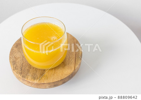 Fresh squeezed orange juice in glass on table on white background. Healthy beverage for breakfast Fresh squeezed orange juice in glass on table on white background. Healthy beverage for breakfast 88809642