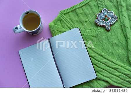 Green sweater, book and a cup of tea on the green background 88811482