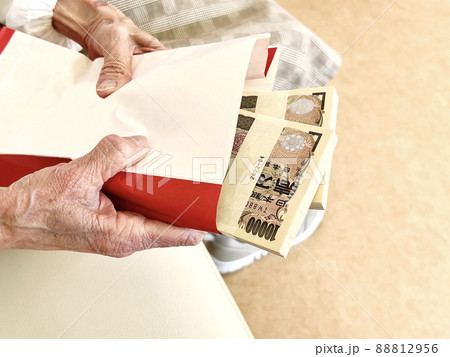封筒に入った200万円の札束を持つ高齢女性の手元 88812956