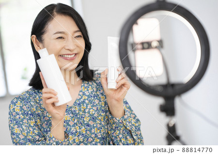 スマホに向かって化粧品をアラフィフの女性　ユーチューバー　ライブコマース　インフルエンサー　イメージ 88814770
