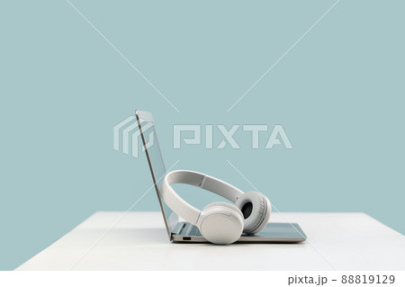 Laptop with wireless headphones on white desk 88819129