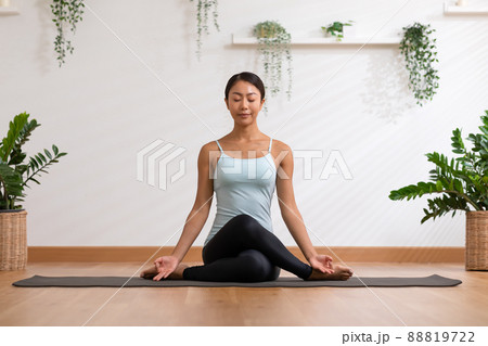 Side view of Asian woman wearing green sportwear doing Yoga exercise,Yoga Child pose or Balasana,Calm of healthy young woman breathing and meditation with yoga at home 88819722