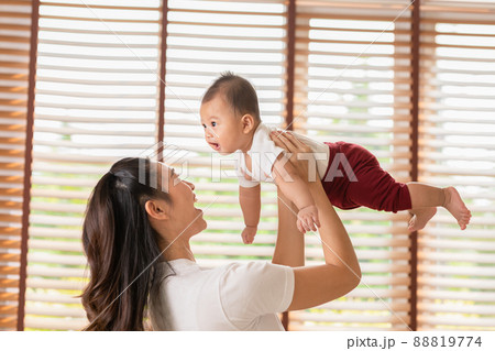 Happy adorable newborn baby playing with mom on bed smiling and cheerful at cozy home.Mom talking with infant baby laughing throwing up newborn baby in the air together.Relax time.Baby and Mother day 88819774