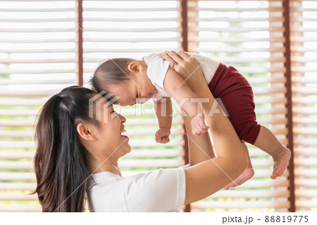 Happy adorable newborn baby playing with mom on bed smiling and cheerful at cozy home.Mom talking with infant baby laughing throwing up newborn baby in the air together.Relax time.Baby and Mother day Happy adorable newborn baby playing with mom on bed smiling and cheerful at cozy home.Mom talking with infant baby laughing throwing up newborn baby in the air together.Relax time.Baby and Mother day 88819775