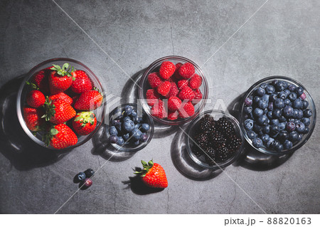 Assorted berries in glass bowls on dark background top view. Assorted berries in glass bowls on dark background top view. 88820163