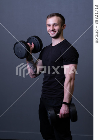 A guy with dumbbells in a black T-shirt muscular man sport posing, from aged grey in guy and workout athletic, attractive caucasian. Active bodybuilder exercise, gym young 88821713