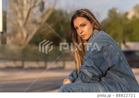 Young woman sitting outdoors looking at camera Young woman sitting outdoors looking at camera 88822721