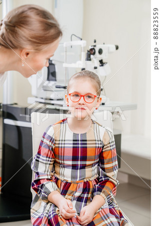 ophthalmologist picks up glasses for a little girl at an appointment in a clinic ophthalmologist picks up glasses for a little girl at an appointment in a clinic 88823559