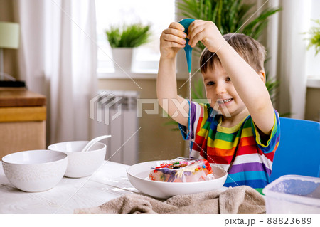 A cute little child pours warm water over toys frozen in ice. Dinosaur defrosting. Early development A cute little child pours warm water over toys frozen in ice. Dinosaur defrosting. Early development 88823689