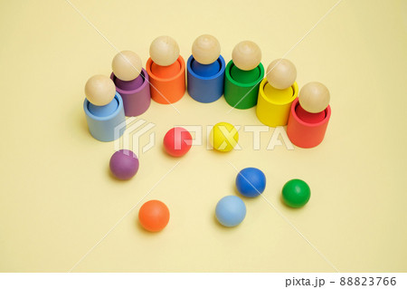 A modern children's wooden toy for studying flowers, consisting of balls, cups and figures in the shape of a man.The balls are thrown by the kids into a glass of the appropriate color. New game 88823766