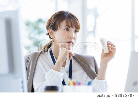 オフィスの自席でサンドイッチを食べるビジネスウーマン 88825787