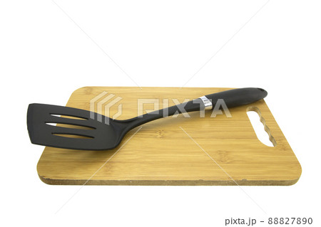 Plastic turner and wooden cutting board isolated on white background. 88827890