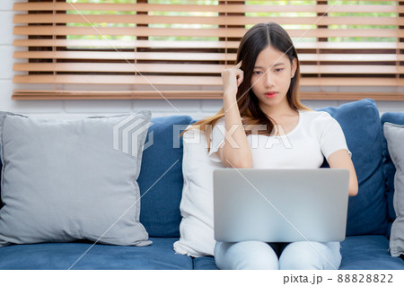 Young asian woman work on laptop computer on sofa at home with frustrated and bored. 88828822