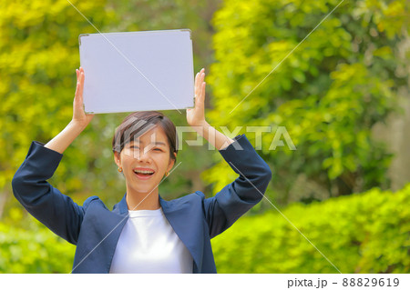 メッセージボードを頭上に掲げるネイビーのジャケットの女性1 メッセージボードを頭上に掲げるネイビーのジャケットの女性1 88829619