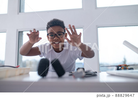 A cute teen sitting at the table and playing with toy wheels A cute teen sitting at the table and playing with toy wheels 88829647