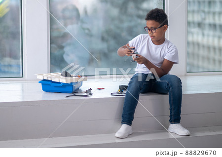 A dark-skinned boy constructing a transformer and looking busy 88829670