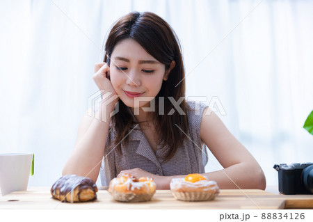 並べたパンを前に座っている若い女性 並べたパンを前に座っている若い女性 88834126