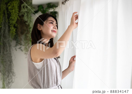 カーテン越しに外を眺めている若い女性 カーテン越しに外を眺めている若い女性 88834147