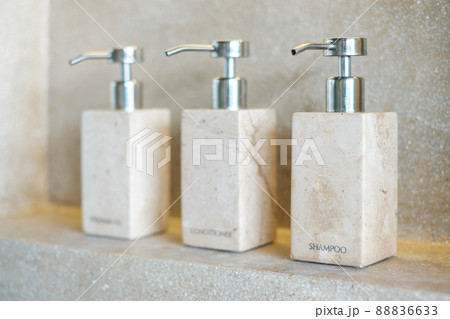 Toiletries bottles in bathroom at luxury hotel or modern home. shower container set, body shower gel, shampoo and hair conditioner in ceramic ware with wall background Toiletries bottles in bathroom at luxury hotel or modern home. shower container set, body shower gel, shampoo and hair conditioner in ceramic ware with wall background 88836633