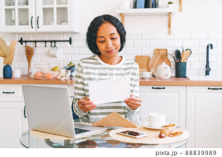 Young African-American female opening and reading paper letter. Concept of receiving correspondence 88839989