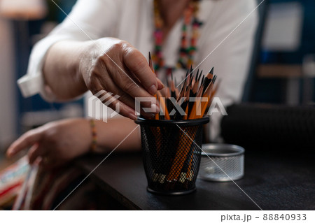 Closeup of elderly woman retired artist hand picking a pencil for making creative traditional art in home studio. Creative older person choosing drawing instrument for still nature sketch. Closeup of elderly woman retired artist hand picking a pencil for making creative traditional art in home studio. Creative older person choosing drawing instrument for still nature sketch. 88840933