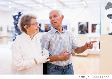 mature European couple examines paintings in an exhibition in hall of art museum 88841722
