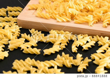 Uncooked Fusilli Pasta Scattered on Wooden Board 88841888
