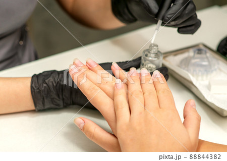 Manicure painting process. Manicure master paint the nails with transparent varnish in a nail salon, close up Manicure painting process. Manicure master paint the nails with transparent varnish in a nail salon, close up 88844382