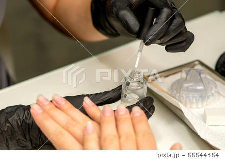 Manicure painting process. Manicure master paint the nails with transparent varnish in a nail salon, close up Manicure painting process. Manicure master paint the nails with transparent varnish in a nail salon, close up 88844384