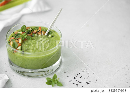 chilled cucumber gazpacho with tomato pieces and basil in a glass bowl, copy space 88847463