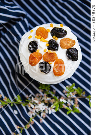 Easter cake, decorated with dried apricots and prunes, stands on a striped blue apron, a flowering branch. Easter religious holiday concept. Easter cake, decorated with dried apricots and prunes, stands on a striped blue apron, a flowering branch. Easter religious holiday concept. 88849879