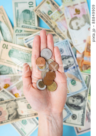 The girl holds coins in her hands against the background of scattered banknotes. International banknotes - dollars, euros, coins. The concept of currency transactions, loans, exchange, gambling. 88849909