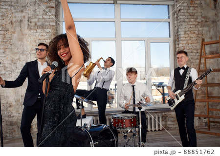 Repetition of multi ethnic jazz band in loft. Bass guitar player, electric guitar player, saxophonist and drummer at loft. Jazz music and jam session concept. passion for music and youth culture 88851762