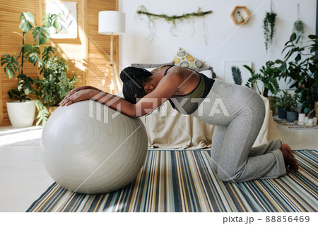 African pregnant woman standing on knees leaning on fitness ball feeling pain during contractions, she giving birth at home 88856469