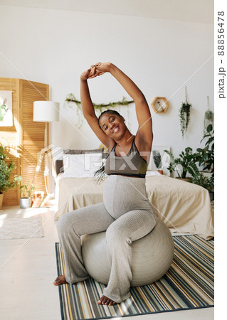 African young woman doing exercises on fitness ball in her bedroom during pregnancy African young woman doing exercises on fitness ball in her bedroom during pregnancy 88856478