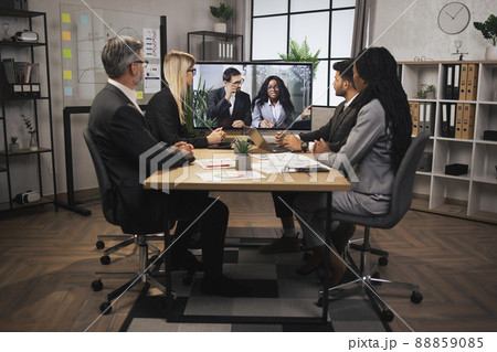 Team of four focused multiethnical businesspeople looking at screen, having video conference in modern office 88859085