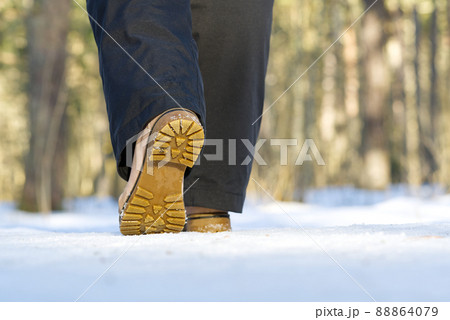 Woman walking on snow in winter forest. Focus on sole of show with snow. 88864079