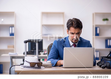 Young male employee preparing for trip at workplace 88866109