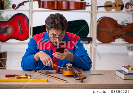 Young man repairing musical instruments at workshop Young man repairing musical instruments at workshop 88866225